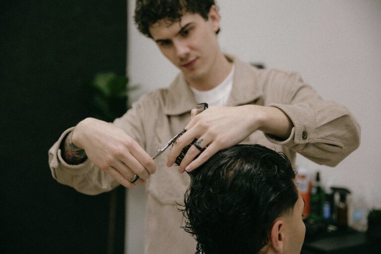 Nico cutting hair in a tan jacket
